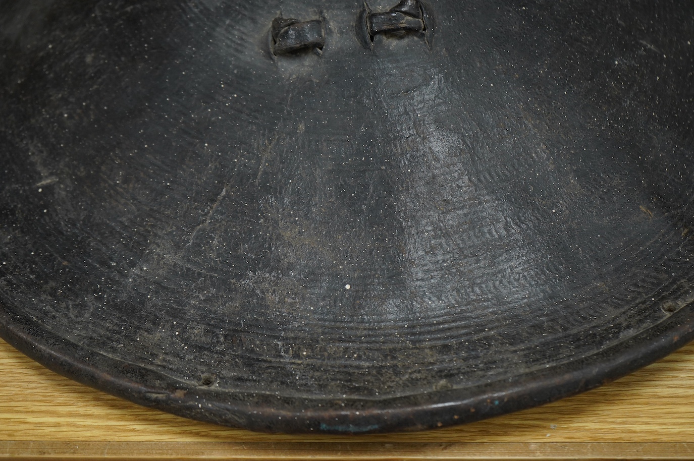 A 19th century Ethiopian/Somali leather shield, 56cm diameter, outside with incised geometric decoration rising to a point, reinforced brim, inside with woven leather handle. Condition - good.